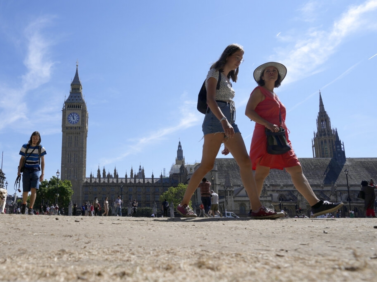 Tourists walk across a parched stretch of grass in Parliament Square outsid...