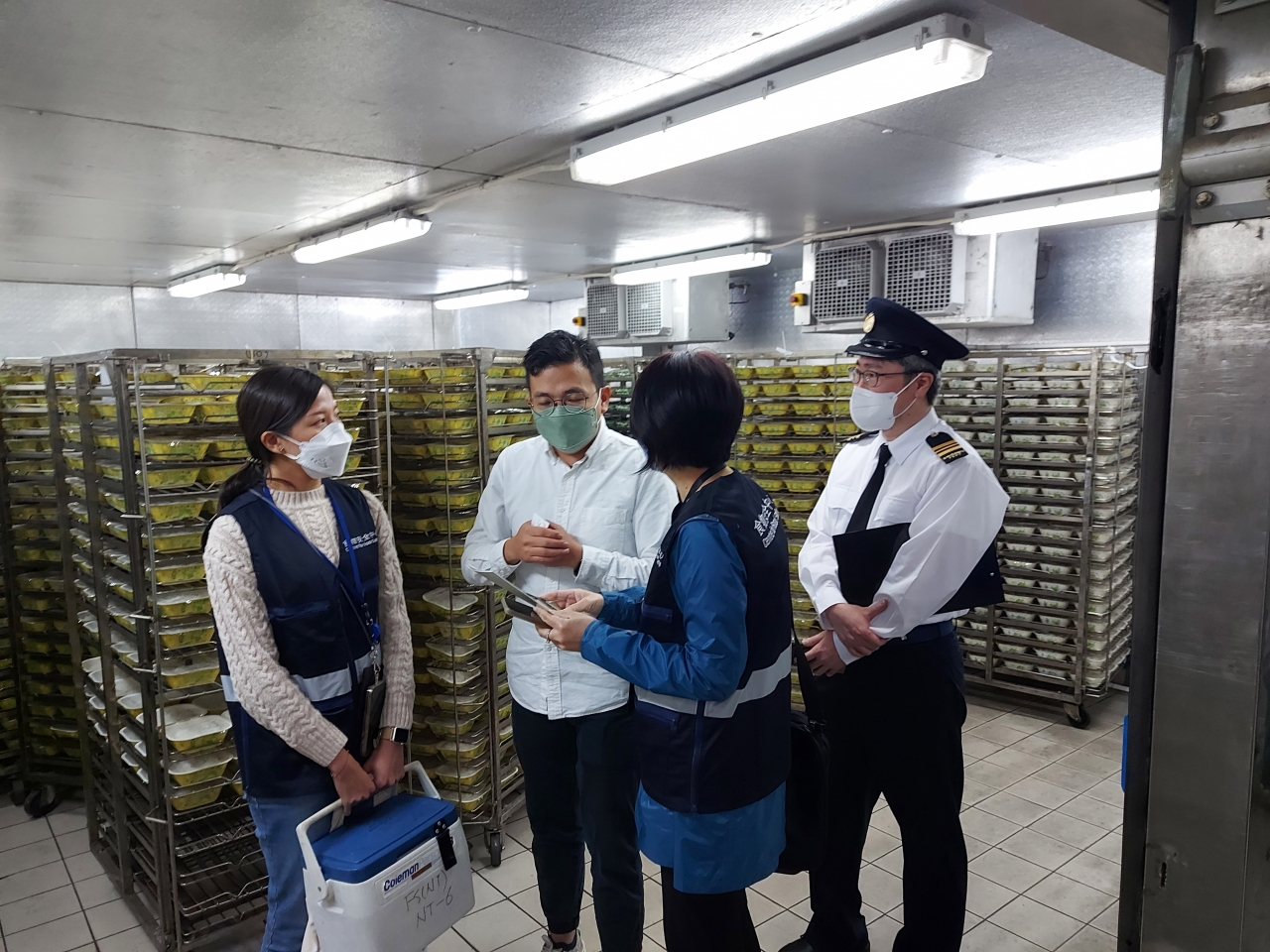 食環署人員在行動中檢取食物樣本化驗，並向食物業處所負責人派發食物安全小冊子，提醒處理學生飯盒的正確方法。（政府新聞處）