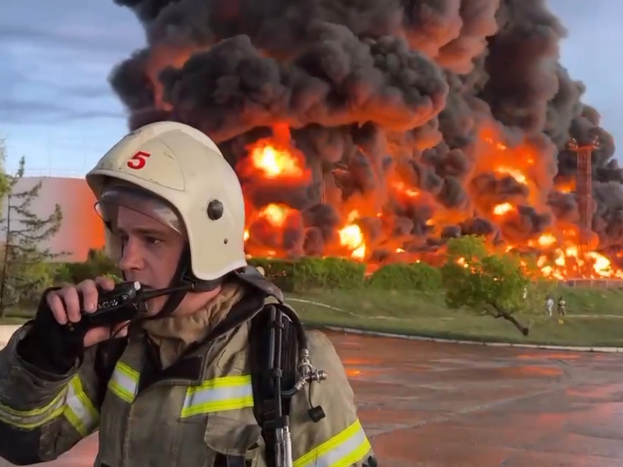 A firefighter speaks on a walkie-talkie as flames rise from a burning fuel tank in Sevastopol. Photo: AP