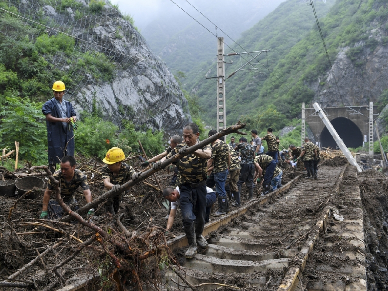 Workers remove fallen debris from a railway track at a flood-hit village in Mentougou district on the outskirts of Beijing. Photo: AP