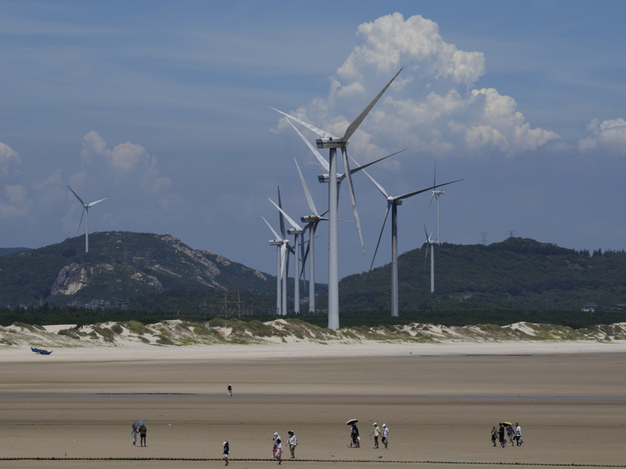 Beachgoers walk near wind turbines along the coast of Pingtan in Fujian province. File photo: AP