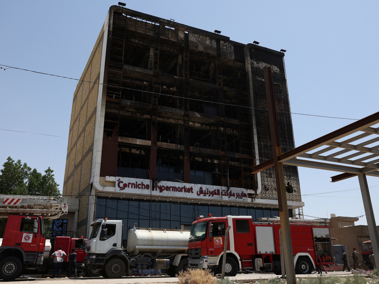 Fire trucks stand next to the wreckage of the shopping centre in Wasit province that caught fire. Photo: Reuters