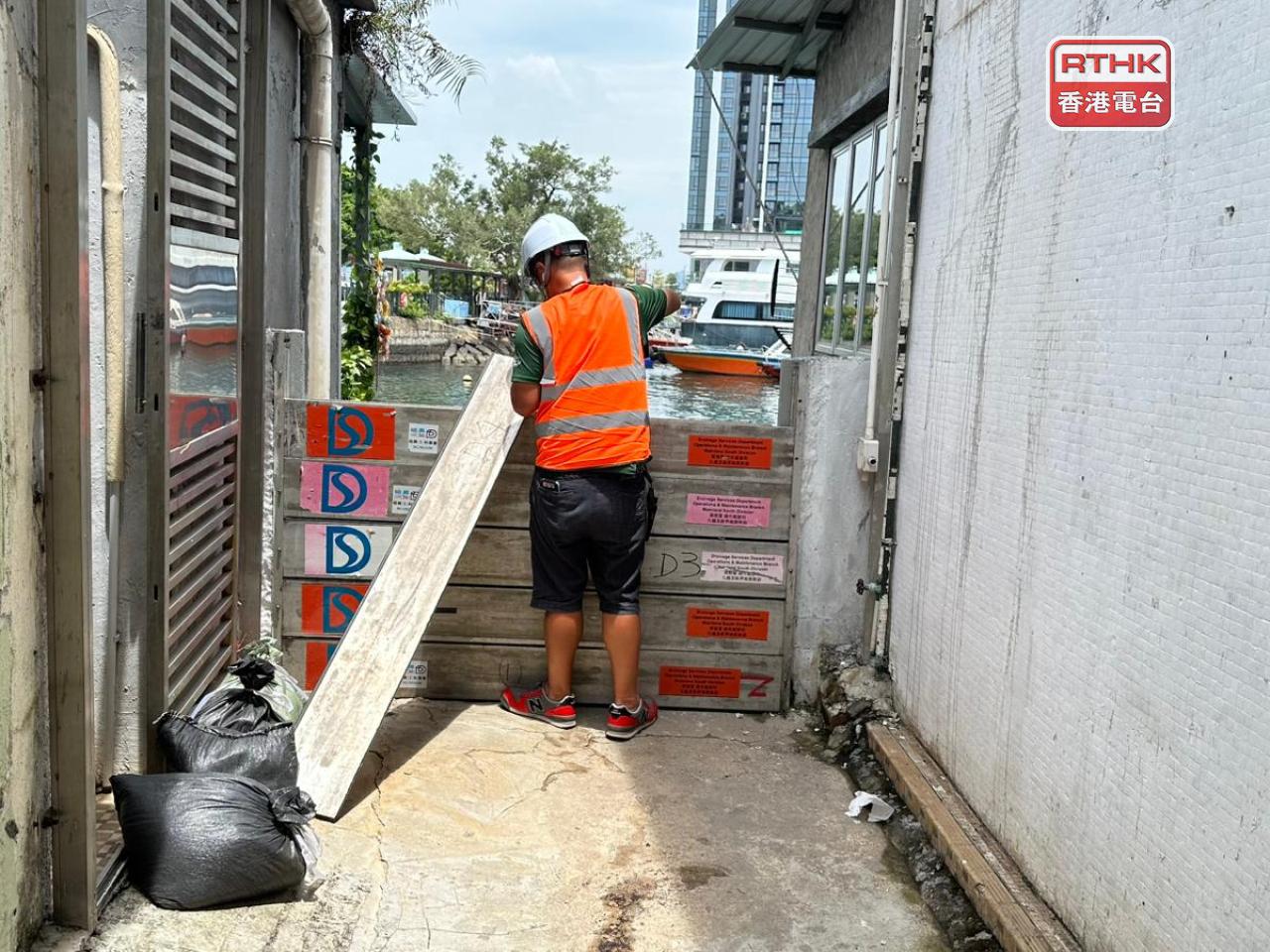 渠務署協助市民安裝擋水板及補充備用沙包。（錢茵彤攝）