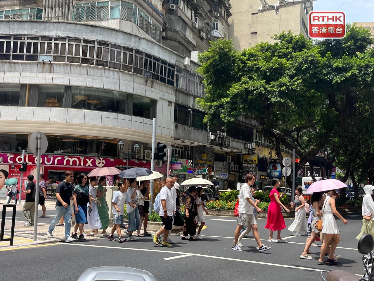 澳門中午天氣酷熱，不少旅客和市民在戶外都要做防曬或用傘出行。（鄭月明攝）