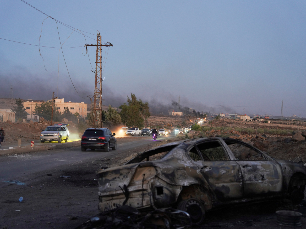 A road in Sweida, Syria, shows the scars of war as buildings burn in the distance on Friday. Photo: Reuters
