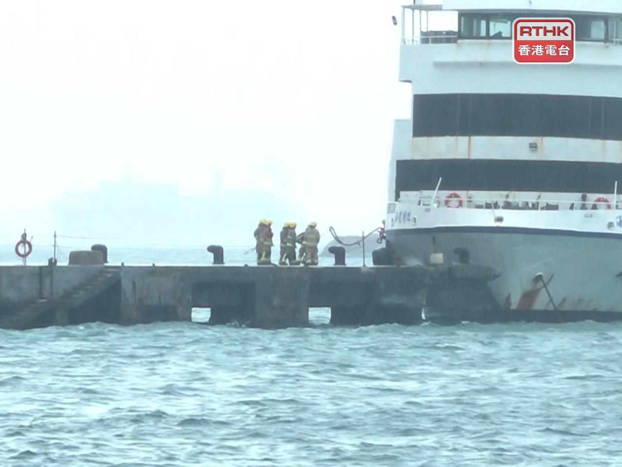 消防輪下午近1時，將涉事船隻推回至碼頭適當位置，多名消防人員再用纜繩將船固定在纜樁。（陳韋丞攝）