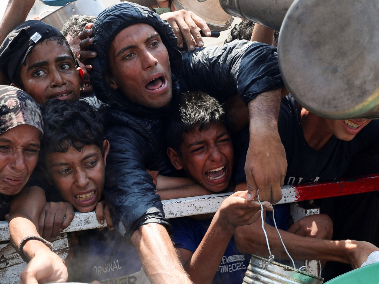 Palestinians react as they wait to receive food from a charity kitchen, amid a hunger crisis. Photo: Reuters