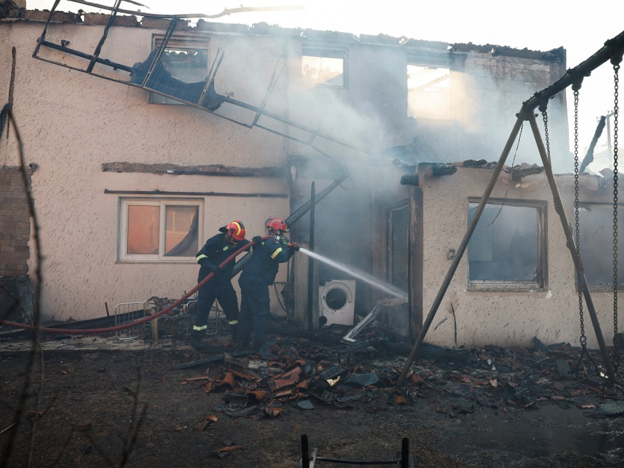 Firefighters try to extinguish flames from a house as a wildfire burns in the village of Kryoneri, near Athens, Greece. Photo: Reuters