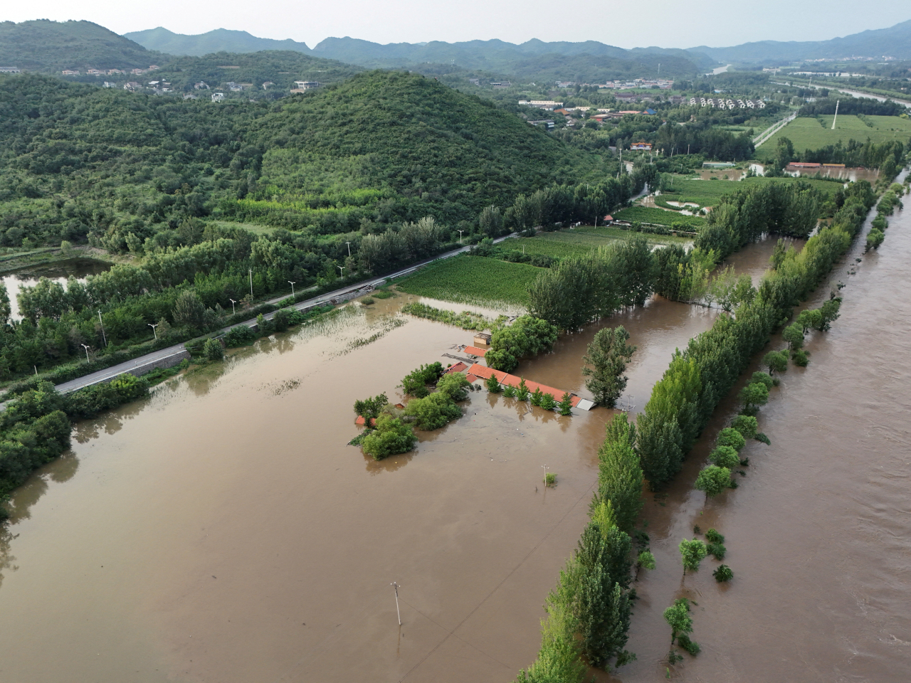 北京密雲區暴雨過後，河水氾濫淹沒附近農地。（路透社）