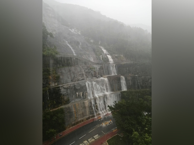 筲箕灣耀興道山邊護土牆出現像「瀑布」的水流，大量沙石夾雜暴雨形成黃泥水傾瀉而下，護土牆幾乎被雨水覆蓋。（梁熙提供）