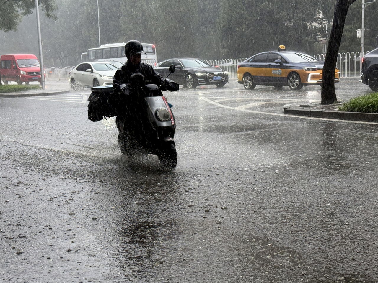 在北京西城區一條街道，一名男子在雨中騎行。（新華社）