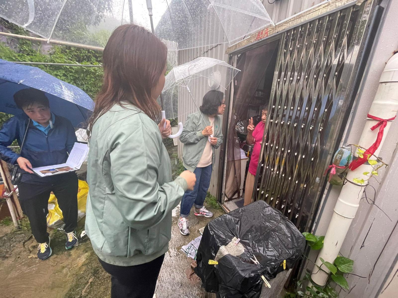 麥美娟（中間雙手持透明傘）探望居民。（民政及青年事務局社交網頁）