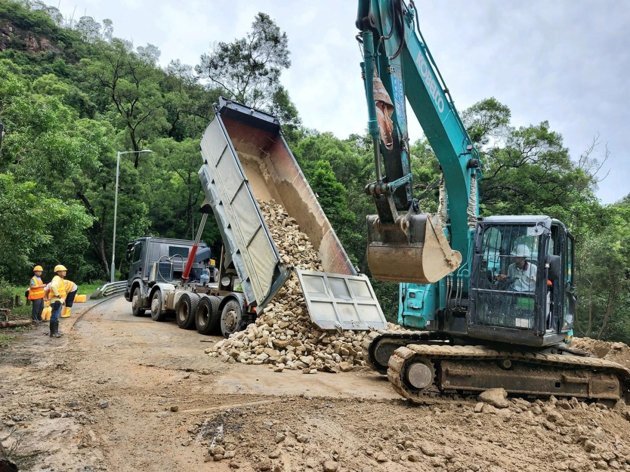 承建商出動多部大型機械，利用堆石填方緊急鞏固斜坡。（路政署社交網頁）