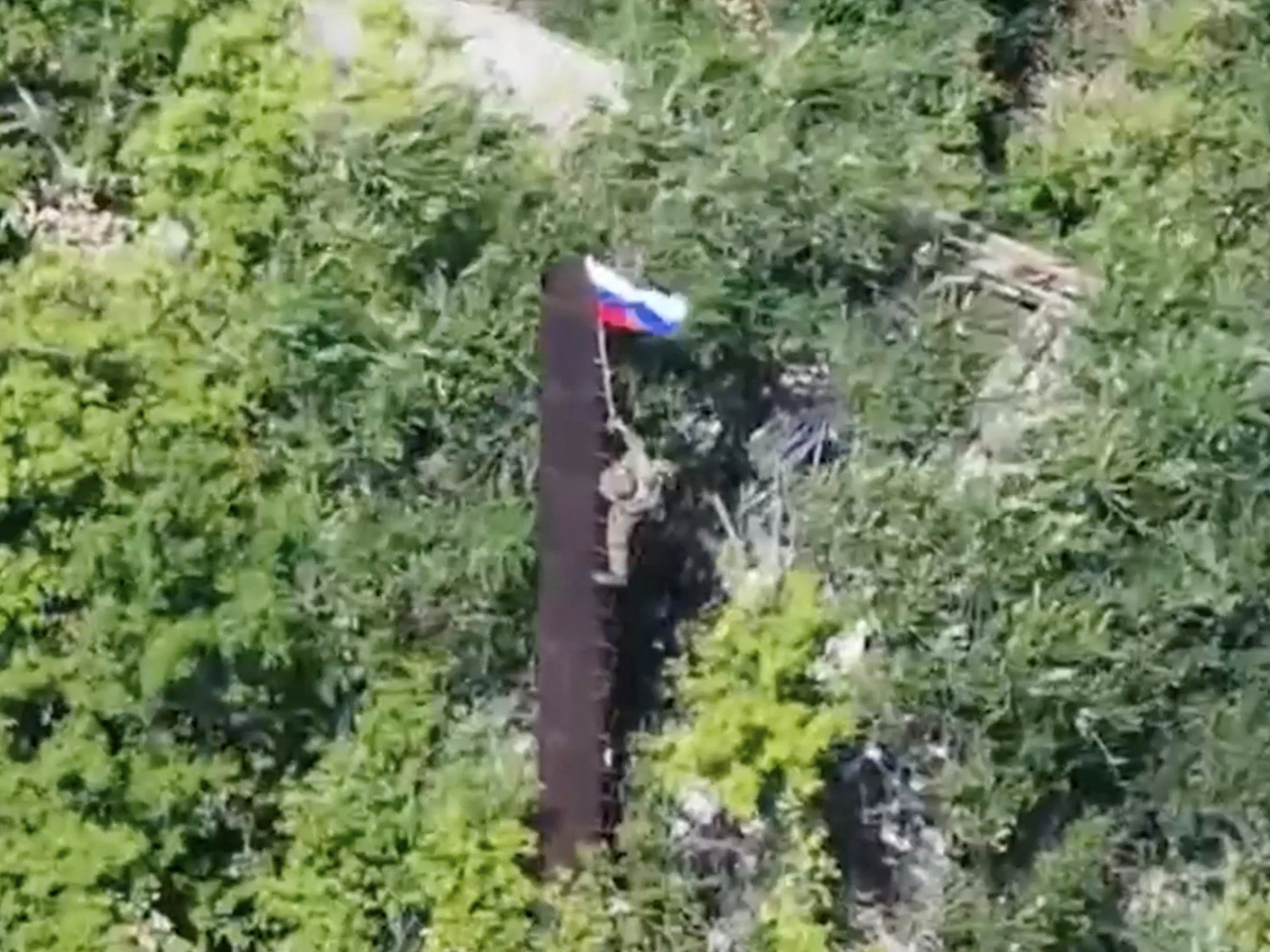 A Russian soldier raises his country's flag following the capture of a settlement in Ukraine's Donetsk region. File photo: Russian Defence Ministry via Reuters