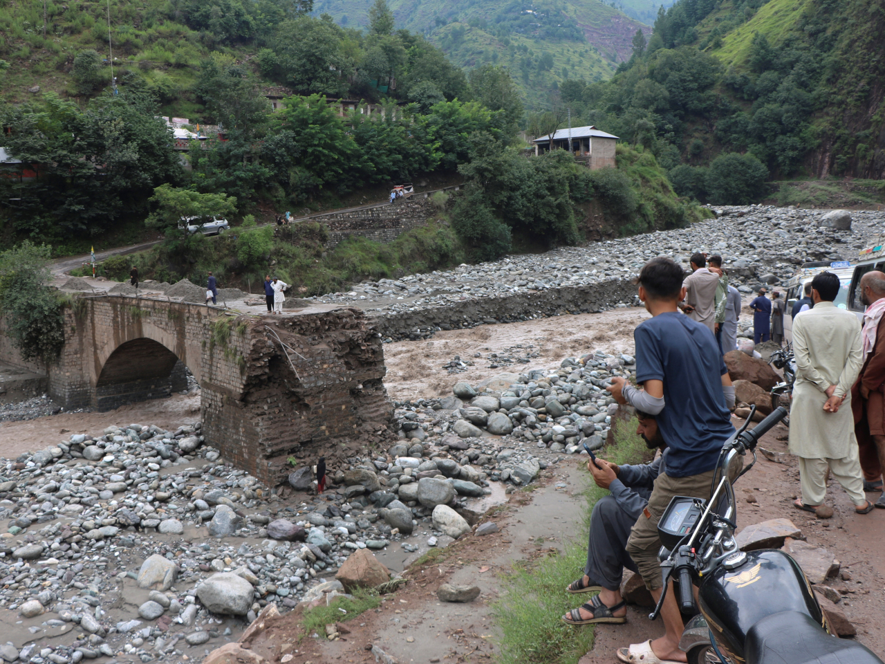 Residents gather at the site of a damaged bridge on the outskirts of Muzaffarabad. Photo: Reuters