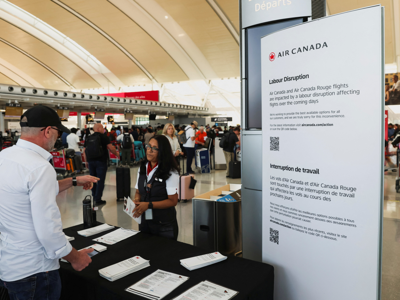 An Air Canada ground staff member addresses the issue of flight disruption with a passenger at Toronto Pearson International Airport. Photo: Reuters