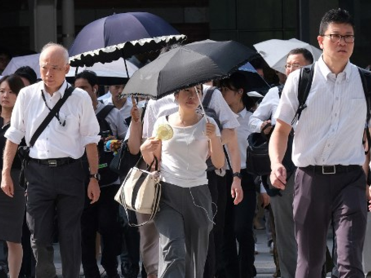 在東京街上，民眾在高溫下撐傘遮擋陽光。 (法新社資料圖片)