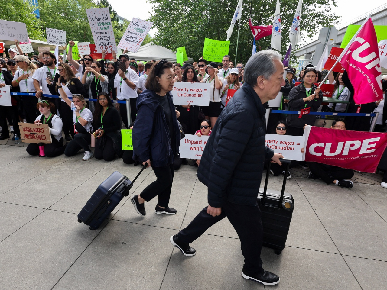 Passengers walk past demonstrators as Air Canada flight attendants said they will remain on strike and challenge a return-to-work order they called unconstitutional. Photo: Reuters