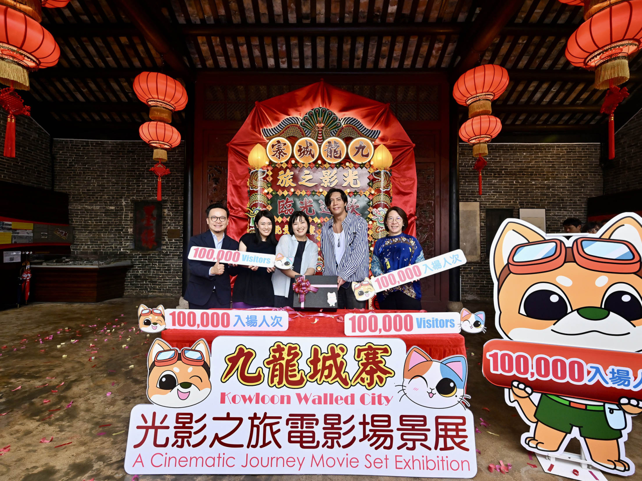 康文署助理署長馮妙玲（右一）與《九龍城寨之圍城》演員張文傑（右二），向第十萬名參觀者（中）送上紀念品。（政府新聞處）