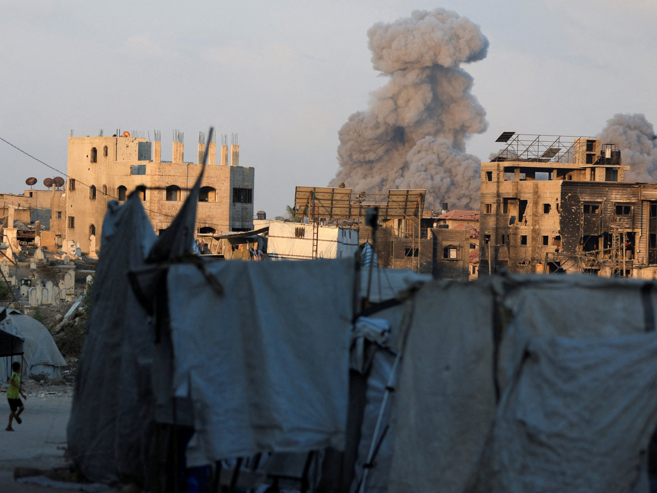 A Palestinian child flees as smoke billows from a building in Gaza City hit by an Israeli airstrike on Thursday. Photo: Reuters
