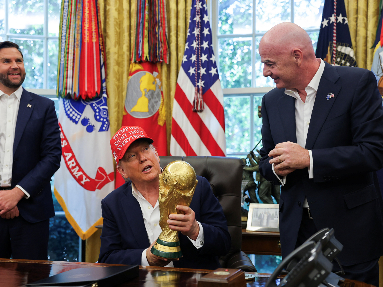 Donald Trump holds the World Cup Trophy, while he makes an announcement on the 2026 World Cup in the Oval Office. Photo: Reuters