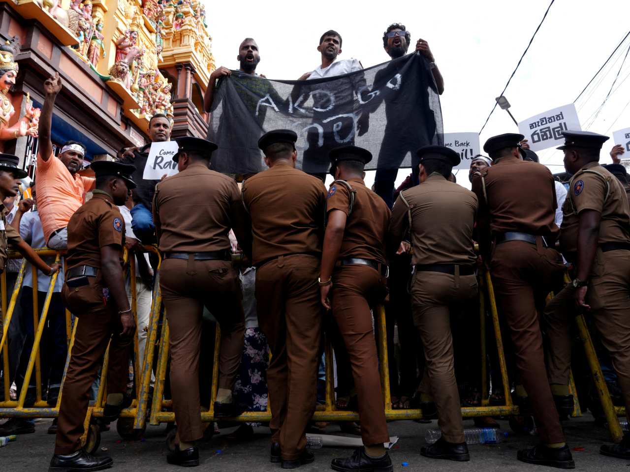 Supporters of Sri Lanka's former president Ranil Wickremesinghe stand on a police barrier as they gather near the magistrate's court ahead of his bail hearing in Colombo. Photo: Reuters