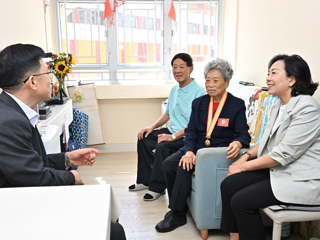 麥美娟（右一）和王松苗（左一）與老兵及其家屬交談。（政府新聞處）