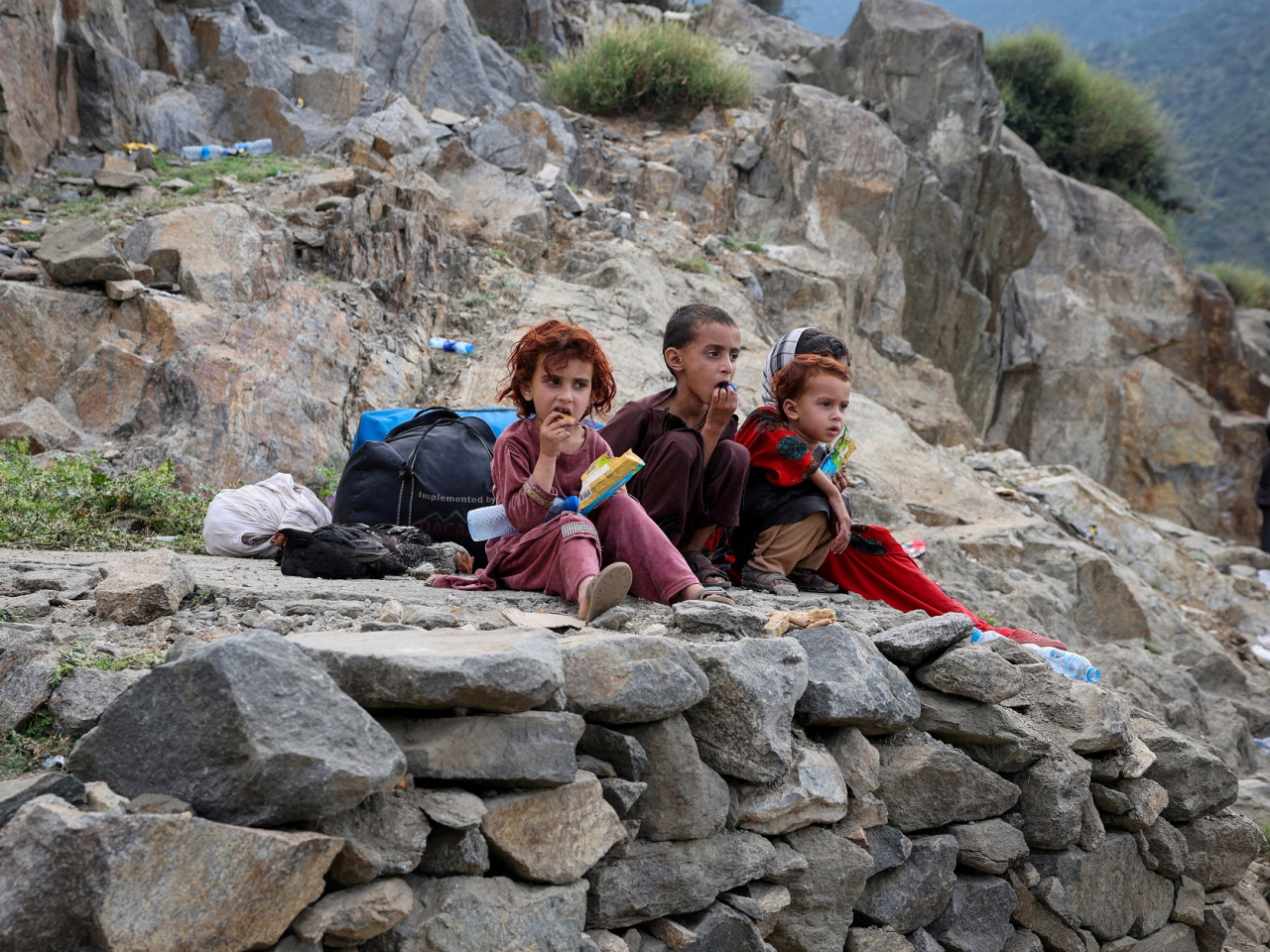 Afghan children sit with their belongings in the devastated village of Mazar Dara. Photo: Reuters