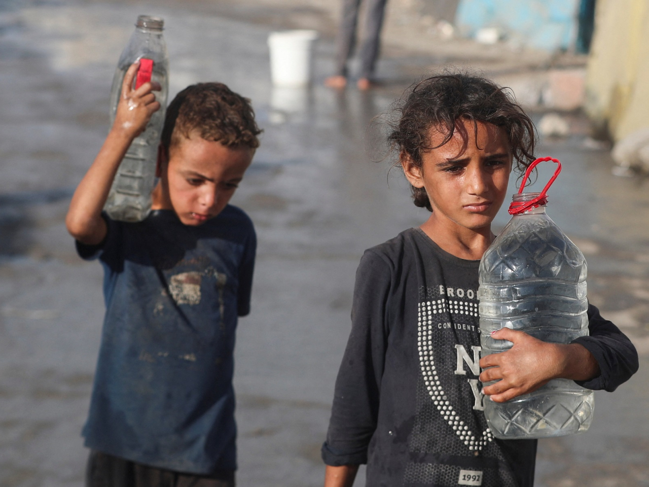 Palestinian children walk with water amid shortages, in Gaza City. Photo: Reuters