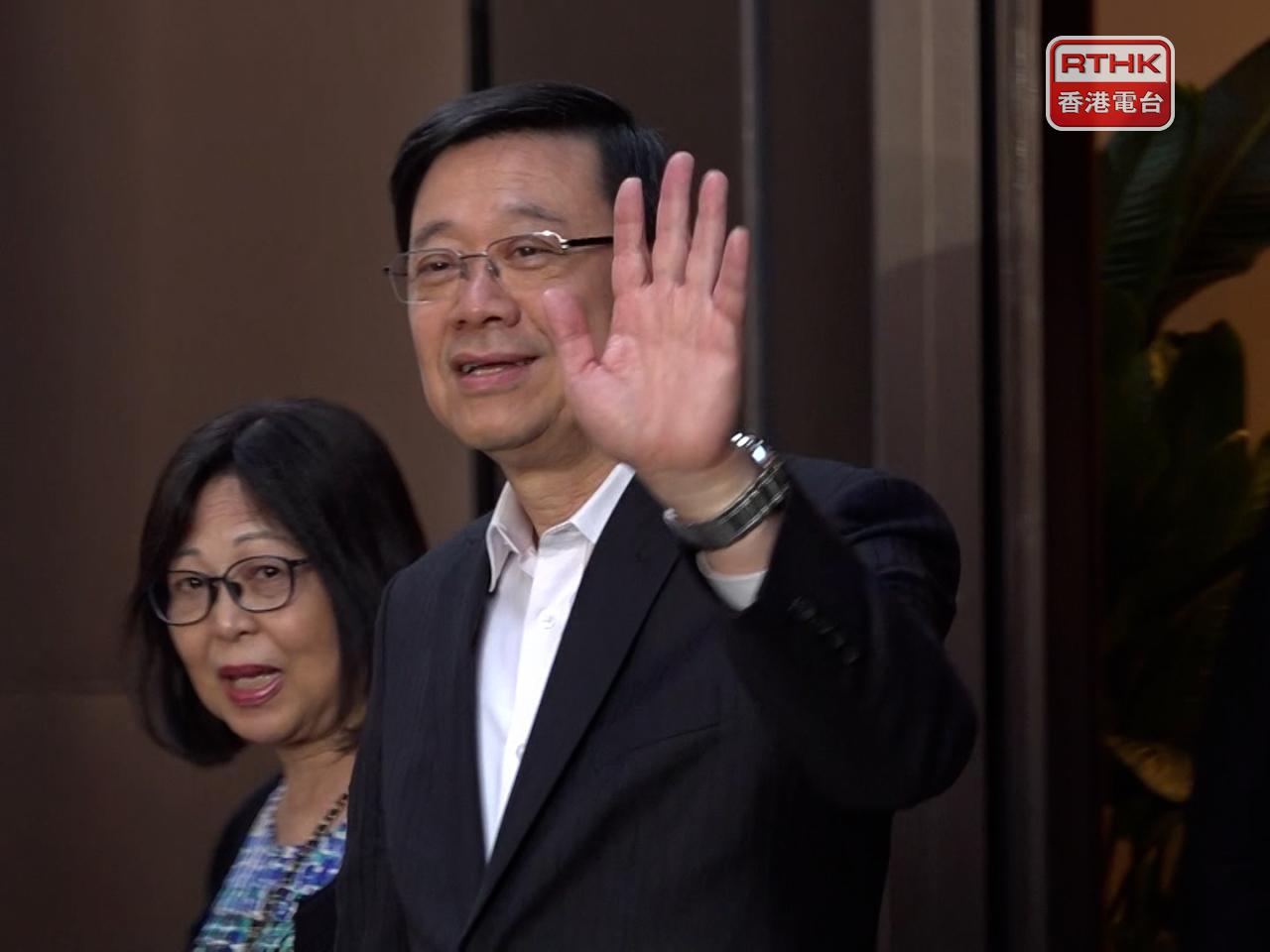 李家超與夫人離開機場時，向在場的記者揮手問好。（陳感恩攝）