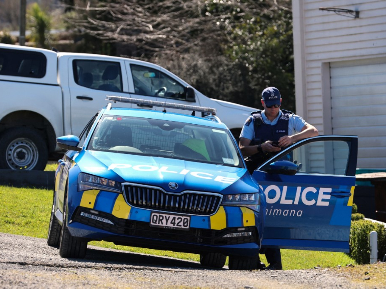 A police officer stands next to his car near a roadblock at a site in the town of Piopio, following a shootout, in New Zealand’s Waikato region. Photo: AFP