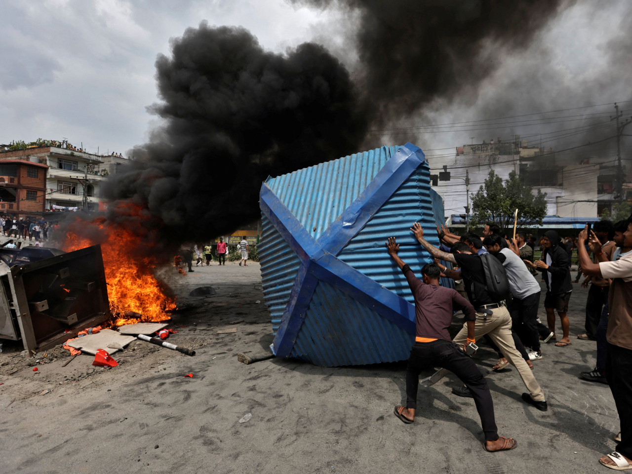 Protesters push a police booth towards a fire outside the  party office of Nepali Congress in defiance of a curfew. Photo: Reuters