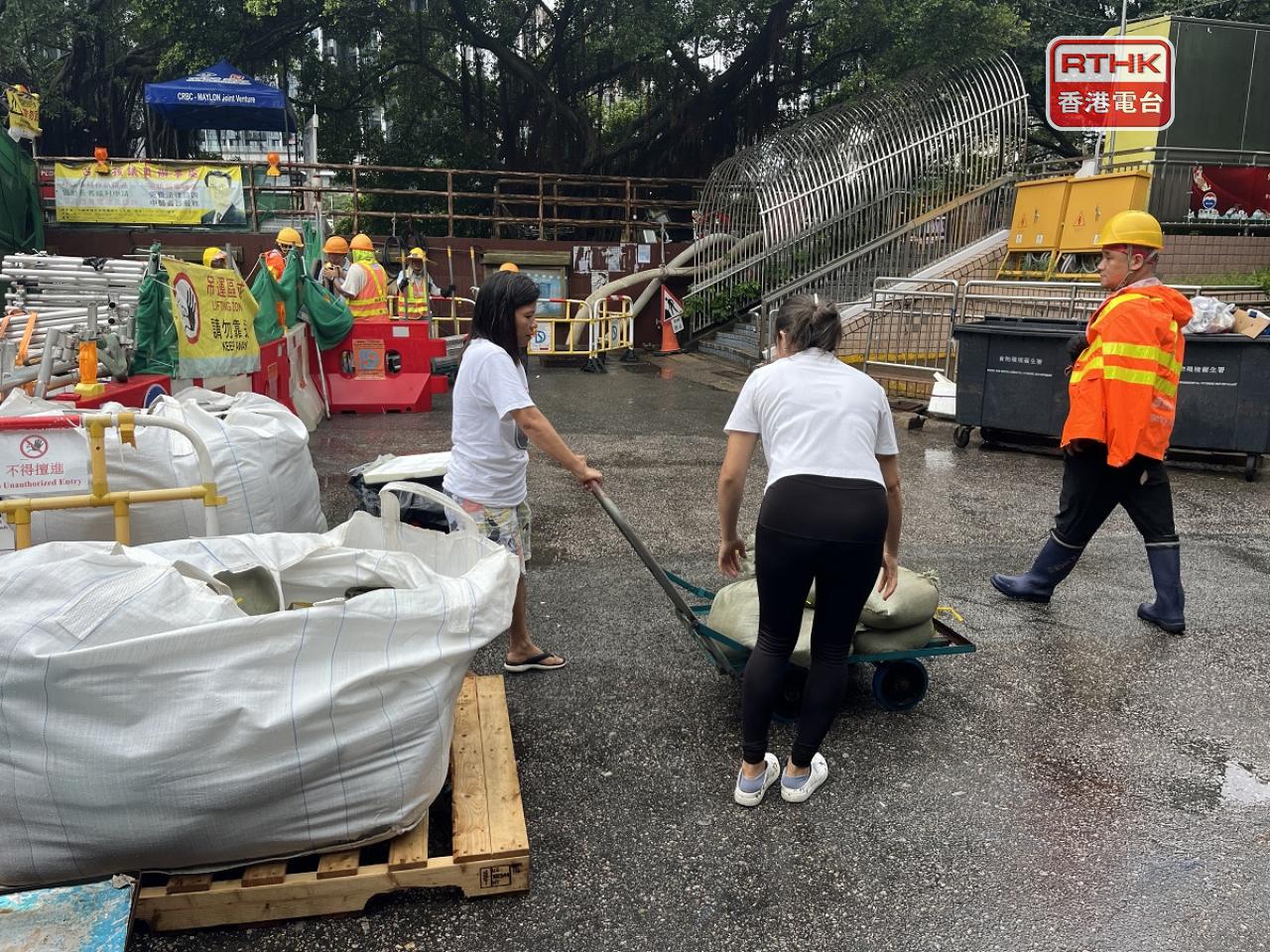 渠務署人員在現場派發沙包，供市民及商戶領取，亦已經設立水閘。（鄧鈞尤攝）