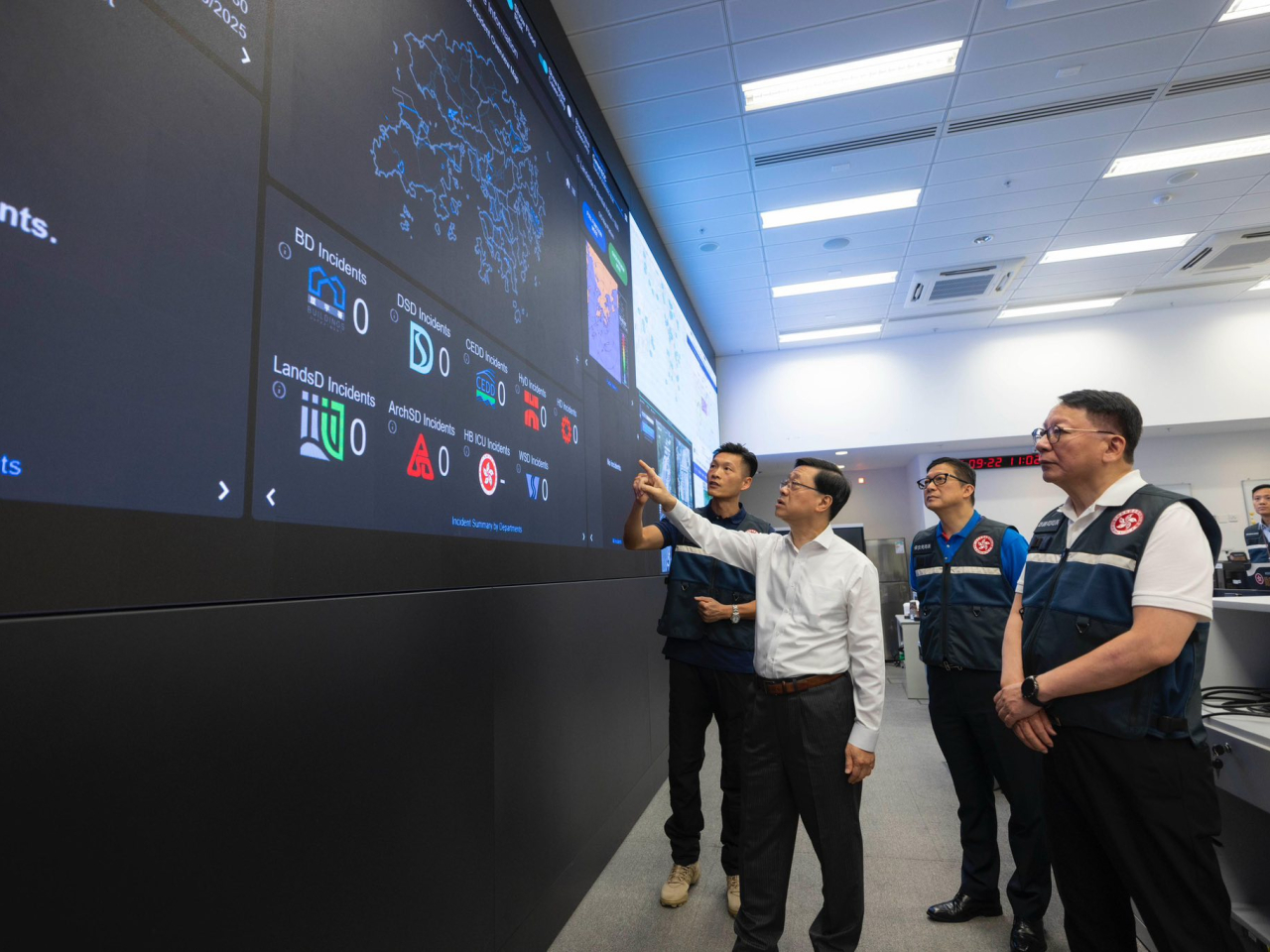 John Lee is briefed on Emergency Monitoring and Support Centre capabilities as Eric Chan and Chris Tang look on. Photo courtesy of chief executive's social media