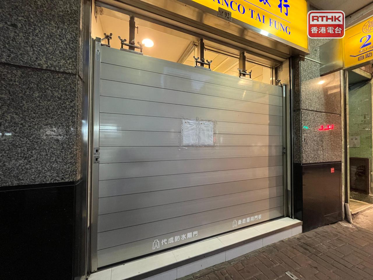 澳門有銀行自助服務點在晚上圍起的水閘比平時高，並貼出告示在颱風期間暫停服務。（鄭月明攝）