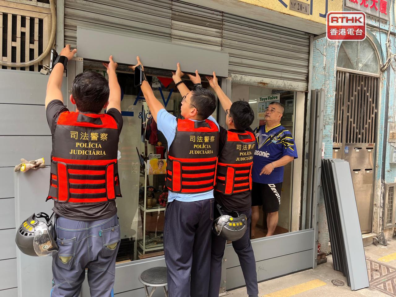 民防中心的司警人員協助低漥地區的小商戶做防浸設施。(鄭月明攝)