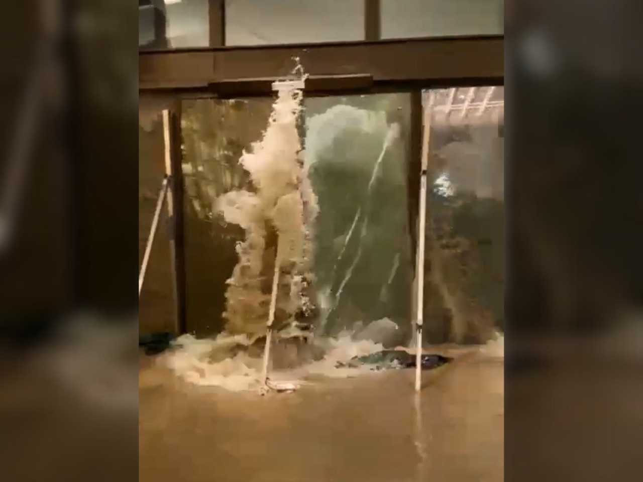 The glass entrance buckles as water surges into the Fullerton Hotel lobby. Photo: social media