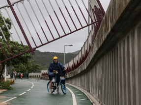 A cyclist looks at a broken fence on a cycle path damaged by Super Typhoon Ragasa. Photo: Reuters