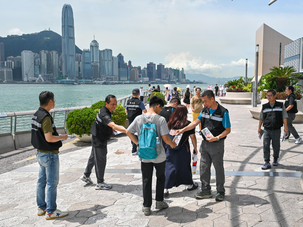 控煙酒辦人員於尖沙咀星光大道向旅客派發有關控煙措施的宣傳單張。（政府新聞處）