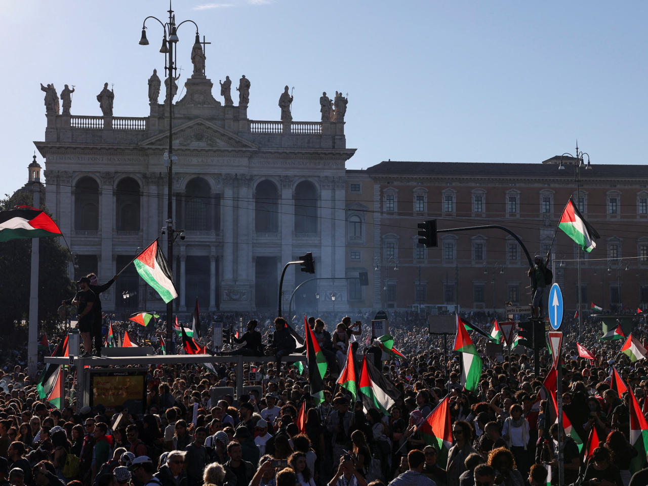 在羅馬市中心,民眾舉起標語及巴勒斯坦旗幟示威抗議。(路透社)