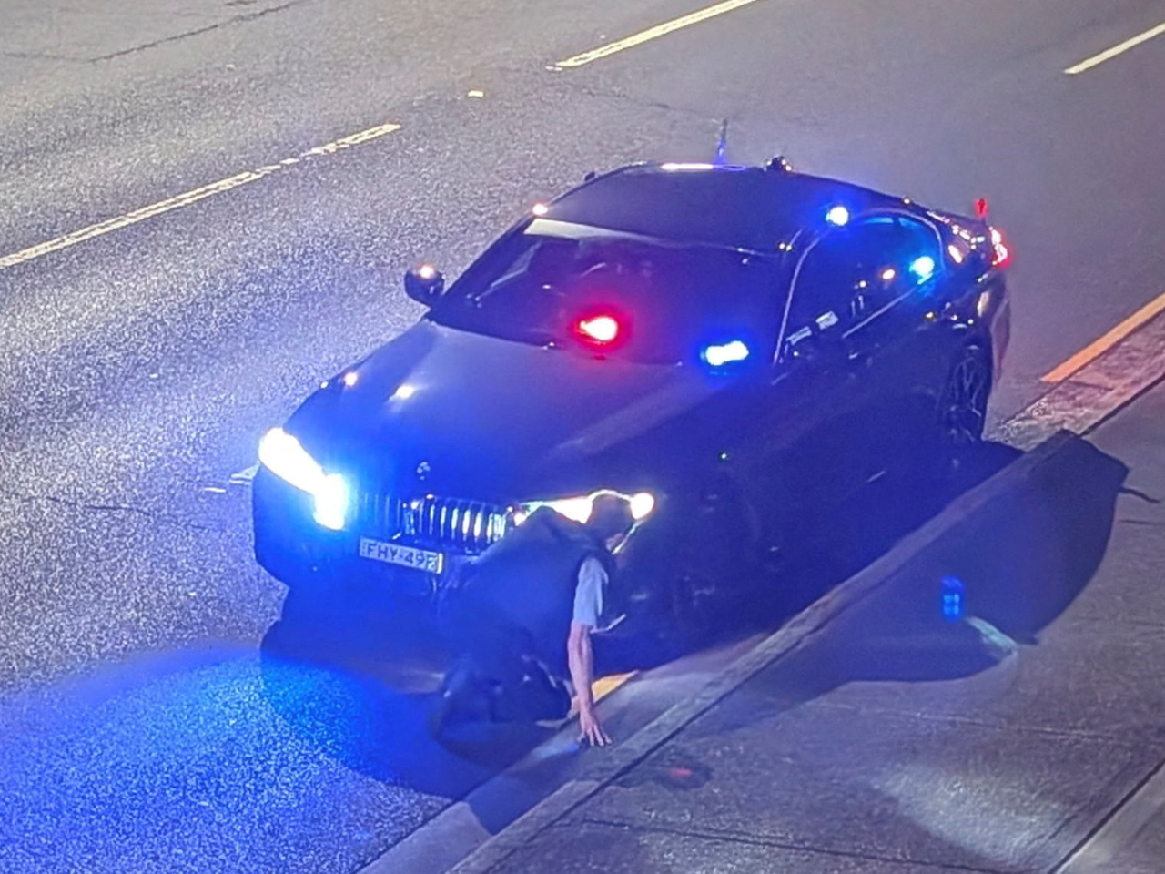 A police officer takes cover behind his cruiser in Croydon Park. Photo: Reuters