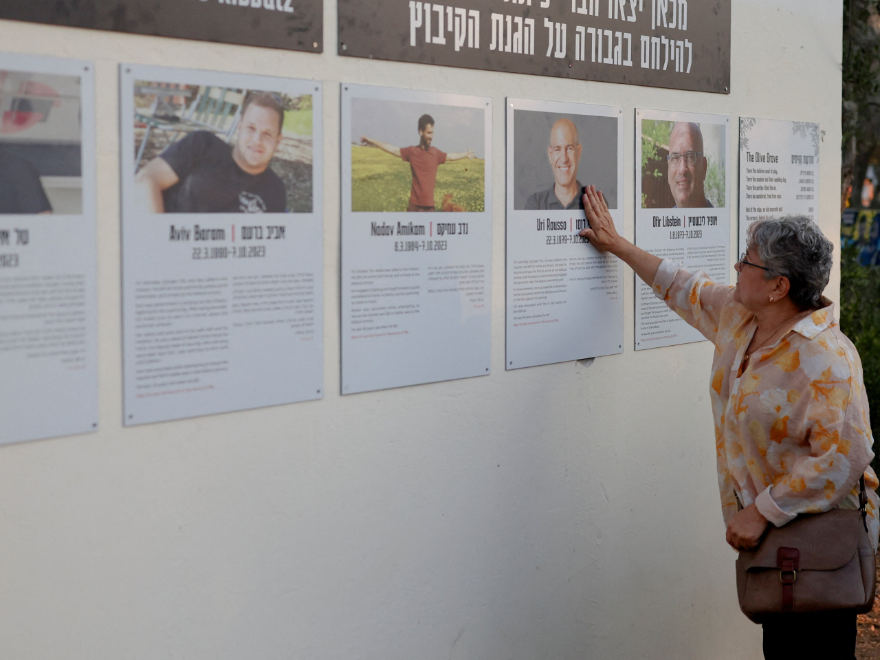 A resident of Kfar Aza, a kibbutz that was one of the worst hit in the October 7, 2023, attack, touches the photo of one of those killed. Photo: Reuters