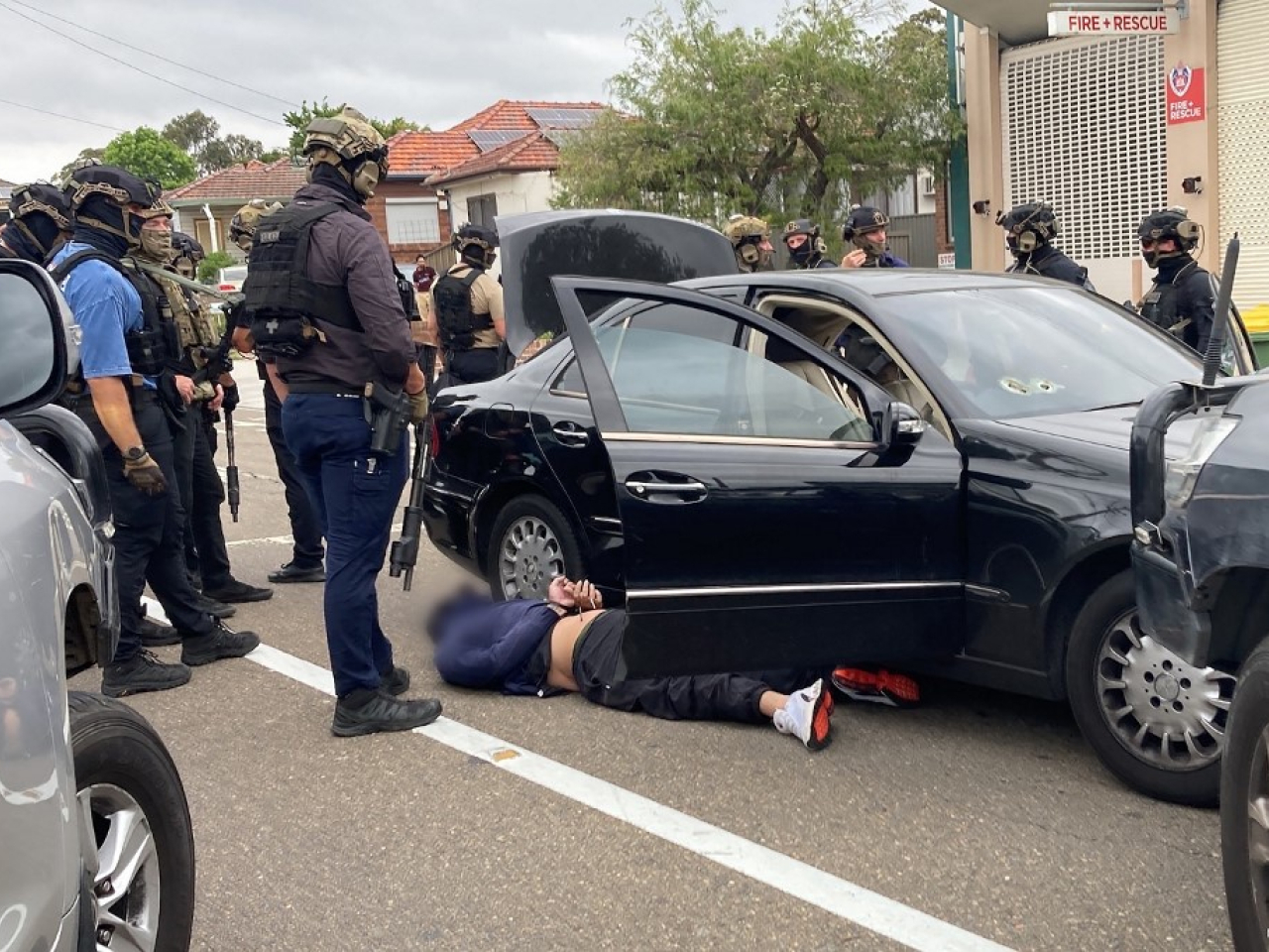 One of the three hitmen can be seen handcuffed in Revesby suburb near the daycare centre. Photo: NSW police/AFP