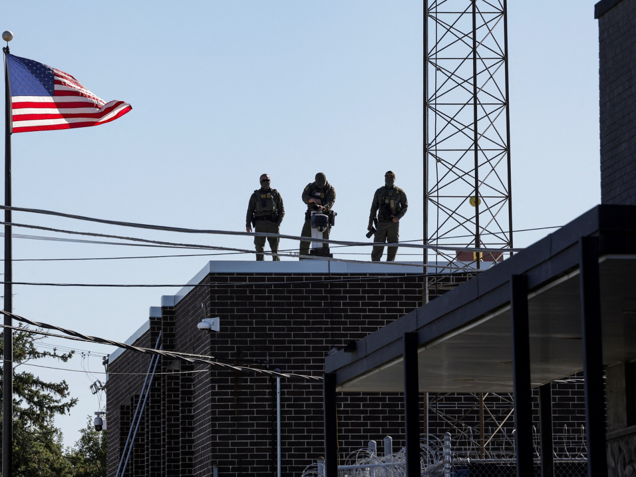 US Border Patrol officers look at protester from the rooftop of the US Immigration and Customs Enforcement (ICE) Broadview facility in Chicago. Photo: Reuters