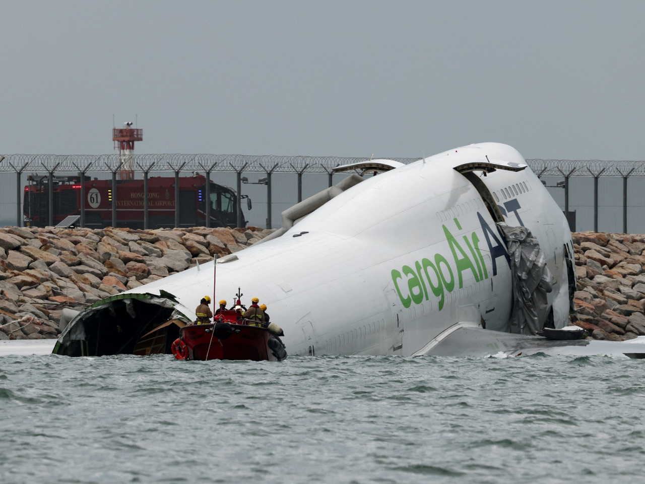 Emergency personnel work near a cargo plane lying partially in the sea after it veered off the runway during landing at Hong Kong International Airport. Photo: Reuters