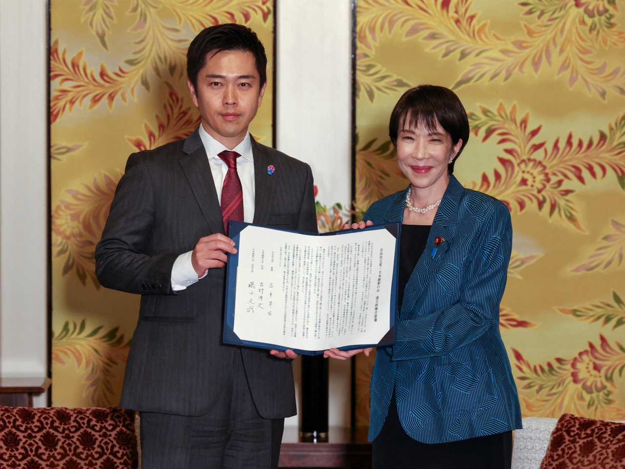 Sanae Takaichi and Japan Innovation Party co-leader Hirofumi Yoshimura show the coalition deal they signed at the National Diet Building. Photo: Reuters