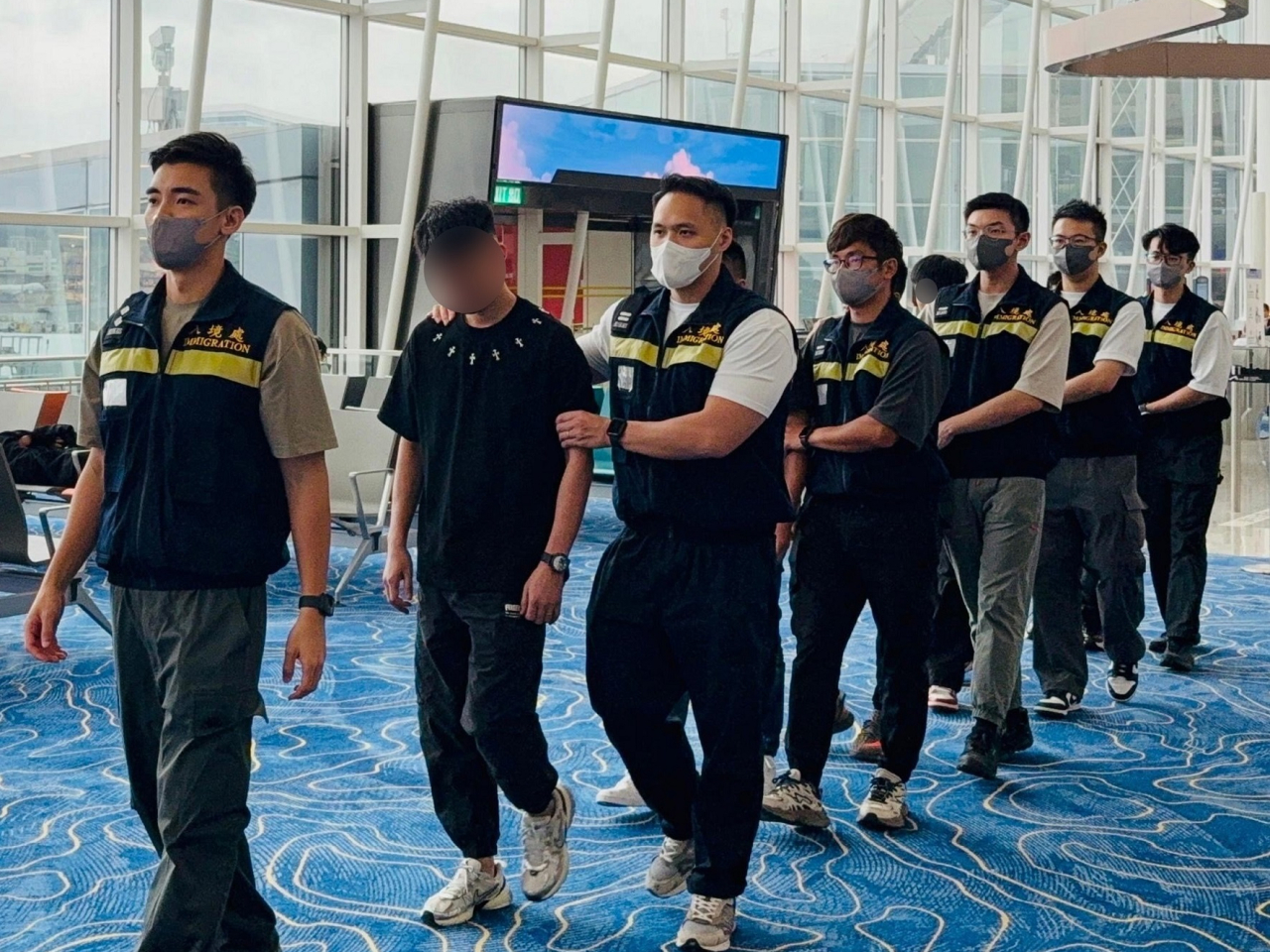 被遣返人士在入境處人員押送下離港。（政府新聞處）