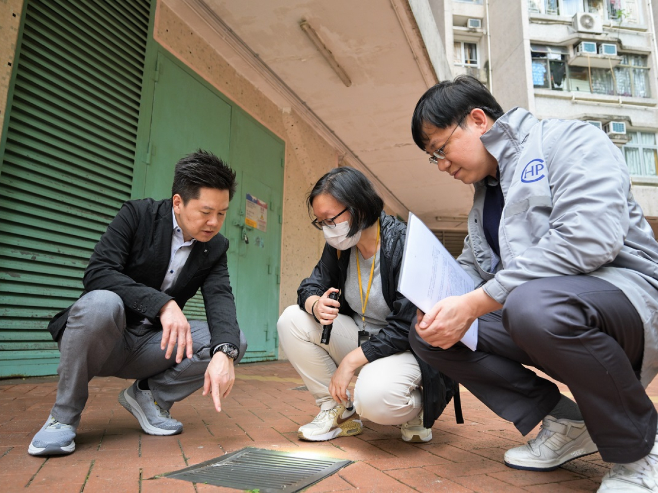 徐樂堅(左)、歐家榮(右)和食環署人員(中)實地視察患者家居一帶的地點,進行病媒調查。(政府新聞處)