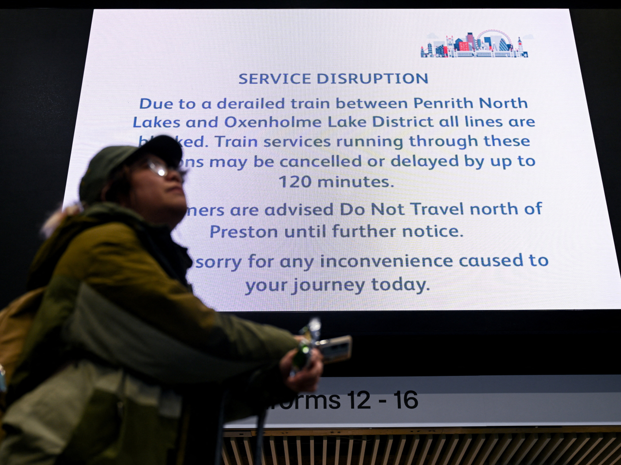 A traveller checks on service delays and cancellations at Euston station following the derailment in Cumbria. Photo: Reuters