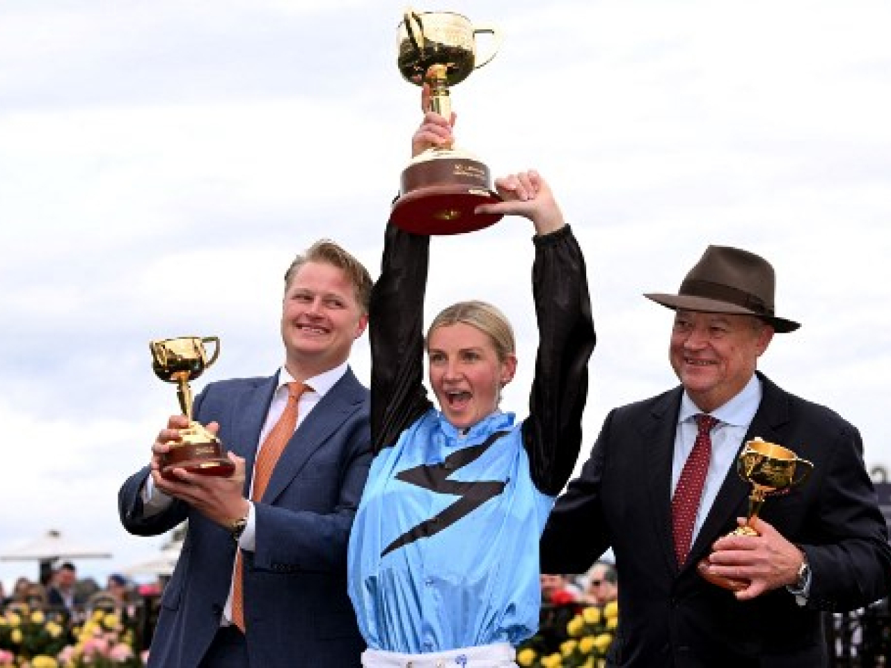 Jamie Melham, centre, holds the trophy after capturing the "race that stops a nation". Photo: AFP